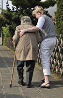 A senior woman walking with the help of a daughter.