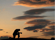 Evening prayer with the silhouette of unrecognizable man kneeling