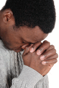 A young African American man with his hands folded praying to God.
