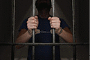An arrested prisoner is holding bars in a prison cell.
