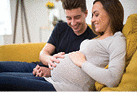 Pregnant Couple Sitting On Sofa