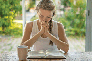 A young woman is reading the Bible and praying in the early morning!