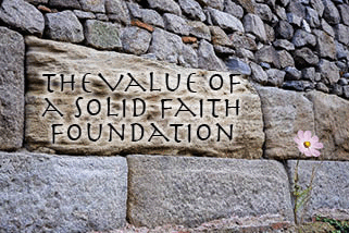 The title of this article is The Value of a Solid Faith Foundation. The background is a stone wall of an ancient building with unusual huge stones in the base. The flower next to it symbolizing the opportunities of a solid foundation.
