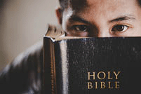 <strong>Close-up of young man student reads a Holy Bible and looks at the camera.</strong>!
