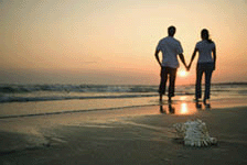 Back view of mid-adult couple holding hands walking on a beach