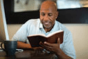 African American man praying and reading the Bible.