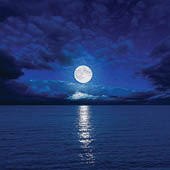 Full moon in clouds over water.
