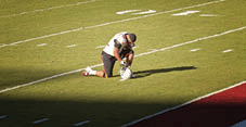 A football player praying on the field.
