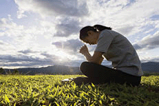 A woman praying in a field.