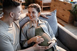 Happy pregnant woman sitting on sofa with her husband