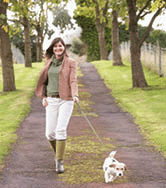 Woman taking a dog for a walk outdoors in a Park
