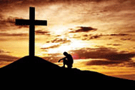 Man near the cross at sunset.