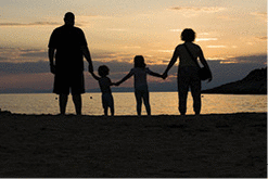 A family is on a beach at sunset