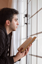 Man with Bible looking out a window.